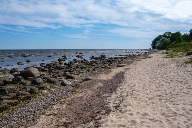 Deniz kenarındaki boş kumlu kumsalda kayalar ve mavi gökyüzü. sessiz meditasyon arkaplanı