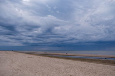 Deniz kenarındaki boş kumlu kumsalda kayalar ve mavi gökyüzü. sessiz meditasyon arkaplanı
