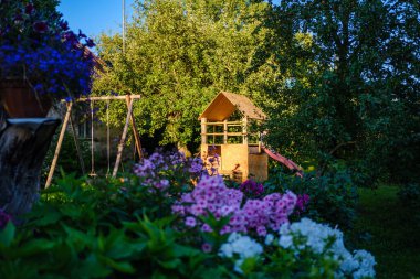 Yazın bahçe bahçesinde eski binalar, çitlerle ve çalılarla süslemeler.