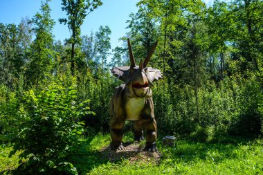 Yapay dinozorlar ve parktaki antik sürüngen heykelleri yaz yeşili ortamda