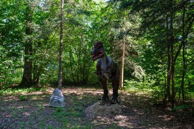 Yapay dinozorlar ve parktaki antik sürüngen heykelleri yaz yeşili ortamda