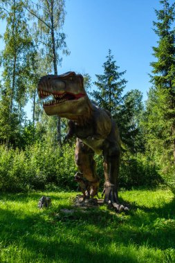 Yapay dinozorlar ve parktaki antik sürüngen heykelleri yaz yeşili ortamda