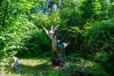 Yapay dinozorlar ve parktaki antik sürüngen heykelleri yaz yeşili ortamda