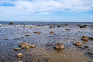 Deniz kenarındaki boş kumlu kumsalda kayalar ve mavi gökyüzü. sessiz meditasyon arkaplanı