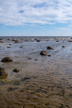 Deniz kenarındaki boş kumlu kumsalda kayalar ve mavi gökyüzü. sessiz meditasyon arkaplanı