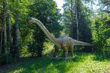 Yapay dinozorlar ve parktaki antik sürüngen heykelleri yaz yeşili ortamda