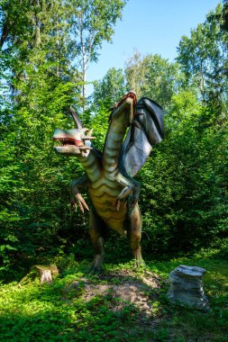 Yapay dinozorlar ve parktaki antik sürüngen heykelleri yaz yeşili ortamda