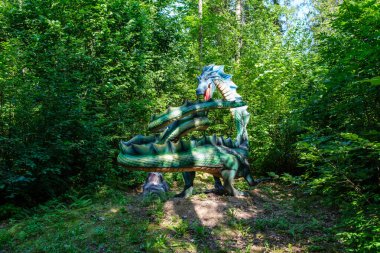 Yapay dinozorlar ve parktaki antik sürüngen heykelleri yaz yeşili ortamda