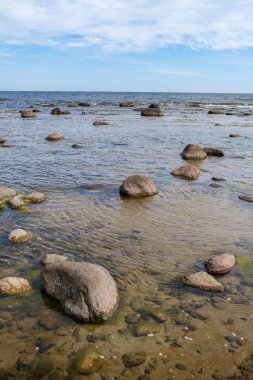 Deniz kenarındaki boş kumlu kumsalda kayalar ve mavi gökyüzü. sessiz meditasyon arkaplanı