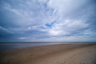 Deniz kenarındaki boş kumlu kumsalda kayalar ve mavi gökyüzü. sessiz meditasyon arkaplanı