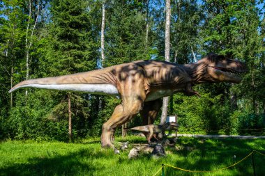 Yapay dinozorlar ve parktaki antik sürüngen heykelleri yaz yeşili ortamda