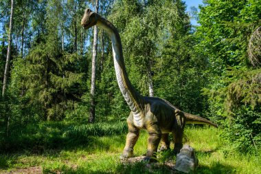 Yapay dinozorlar ve parktaki antik sürüngen heykelleri yaz yeşili ortamda