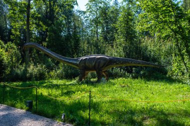 Yapay dinozorlar ve parktaki antik sürüngen heykelleri yaz yeşili ortamda