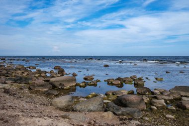 Deniz kenarındaki boş kumlu kumsalda kayalar ve mavi gökyüzü. sessiz meditasyon arkaplanı