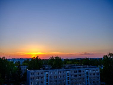 Şehir çatıları üzerinde dramatik renkler ve bulutlarla koyu renkli günbatımı