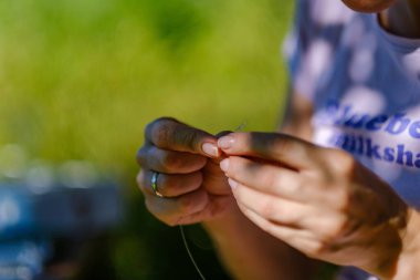 Kadın sanatçı elleri küçük incilerden el yapımı mücevherler yapıyor.