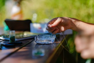Kadın sanatçı elleri küçük incilerden el yapımı mücevherler yapıyor.