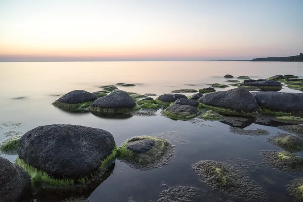 A naplemente, tejes vízzel sziklás strand — Stock Fotó