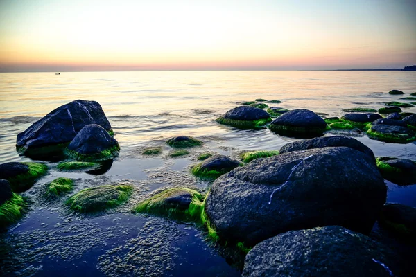 A naplemente, tejes vízzel sziklás strand — Stock Fotó