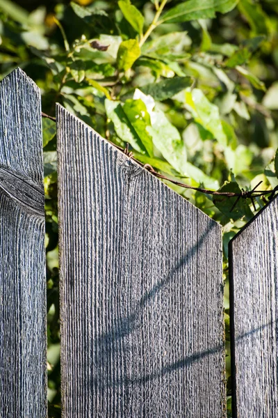 Старый деревянный забор с колючей проволокой сверху — стоковое фото