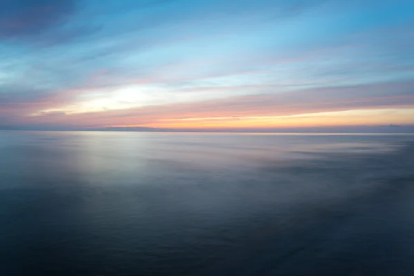 Exposição longa dramático pôr do sol azul com ondas lavadas fora — Fotografia de Stock