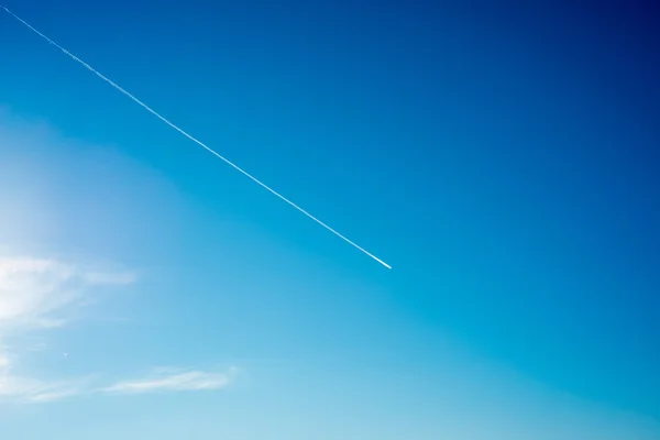 Avion vole dans des nuages blancs dans un ciel bleu et laissant la trace — Photo