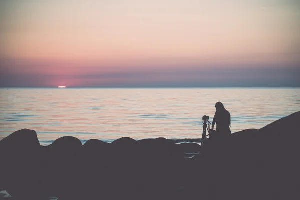 Praia rochosa ao pôr-do-sol com fotógrafo. Vindima . — Fotografia de Stock