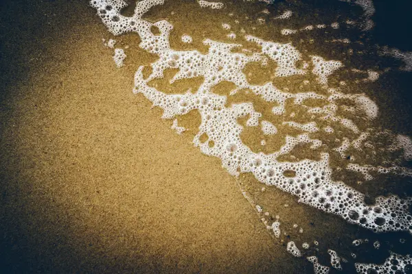 Vagues d'eau se précipitant dans le sable. Retro look film granuleux . — Photo
