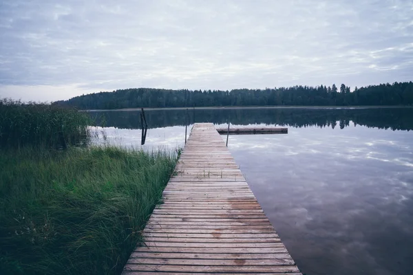 Reflection of clouds in the lake with boardwalk. Retro grainy fi — Stock Photo, Image