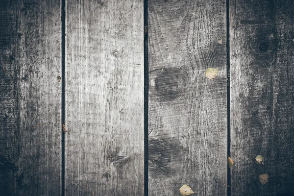 Old wooden planks covered with leaves. Retro grainy film look. — Stock Photo, Image