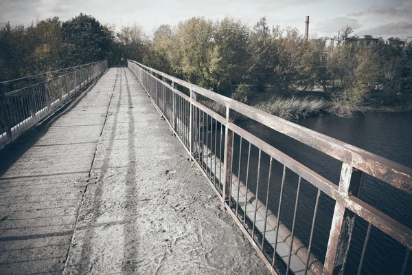 さびた金属レールで古い橋。レトロな粒子の粗いフィルムの外観. — ストック写真