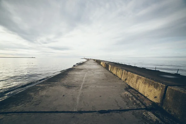 Wellenbrecher im Meer mit Leuchtturm darauf. retro körnigen Film l — Stockfoto