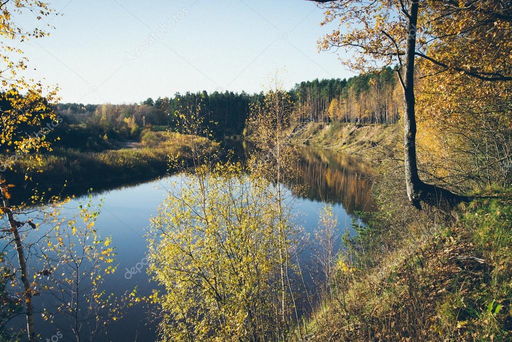 scenic autumn colored river in country. Retro grainy film look.