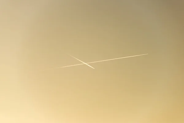 El avión vuela bajo en el cielo, dejando un rastro blanco — Foto de Stock