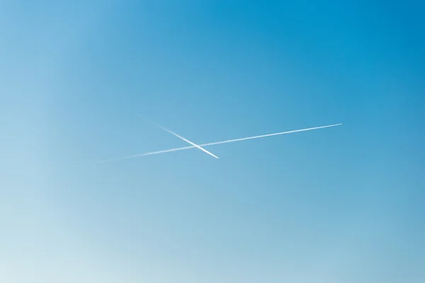 L'avion vole bas dans le ciel, laissant une traînée blanche — Photo