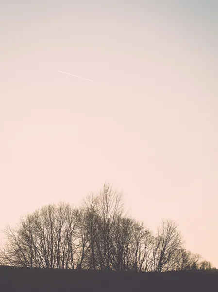 winter sunset with moon and plane trails in the sky. vintage