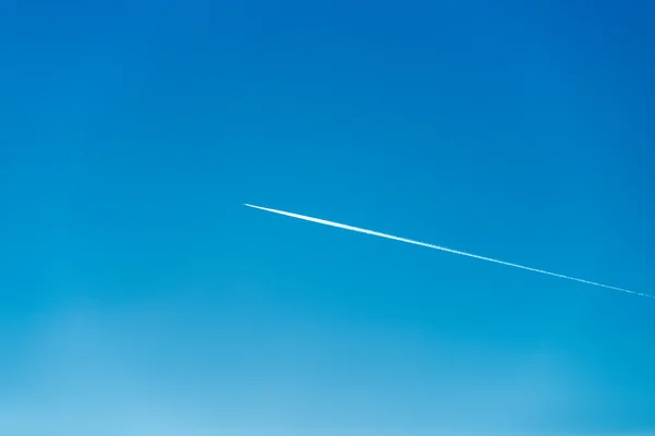 Het vliegtuig vliegt laag in de lucht, waardoor een wit spoor — Stockfoto