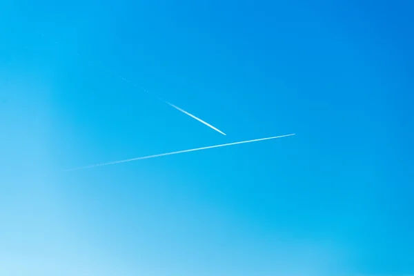 L'avion vole bas dans le ciel, laissant une traînée blanche — Photo