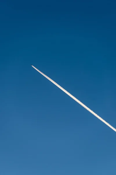 L'avion vole bas dans le ciel, laissant une traînée blanche — Photo