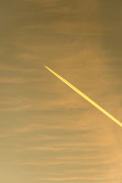 L'avion vole bas dans le ciel, laissant une traînée blanche — Photo