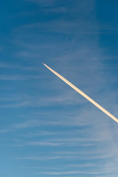 L'avion vole bas dans le ciel, laissant une traînée blanche — Photo