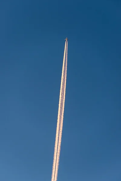 L'avion vole bas dans le ciel, laissant une traînée blanche — Photo