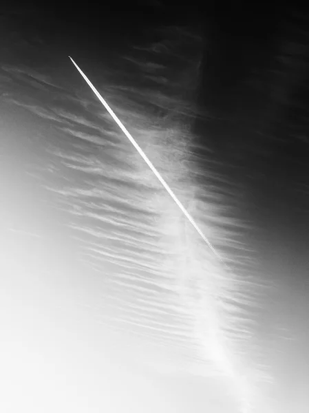 The plane flies low in the sky, leaving a white trail — Stock Photo, Image