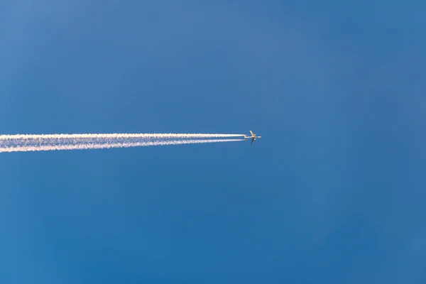 L'avion vole bas dans le ciel, laissant une traînée blanche — Photo