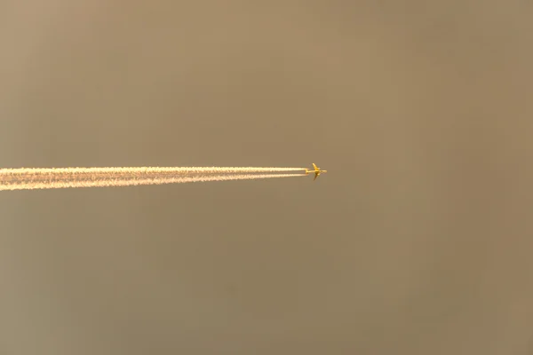 L'avion vole bas dans le ciel, laissant une traînée blanche — Photo