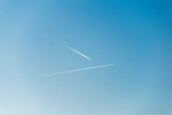 L'avion vole bas dans le ciel, laissant une traînée blanche — Photo