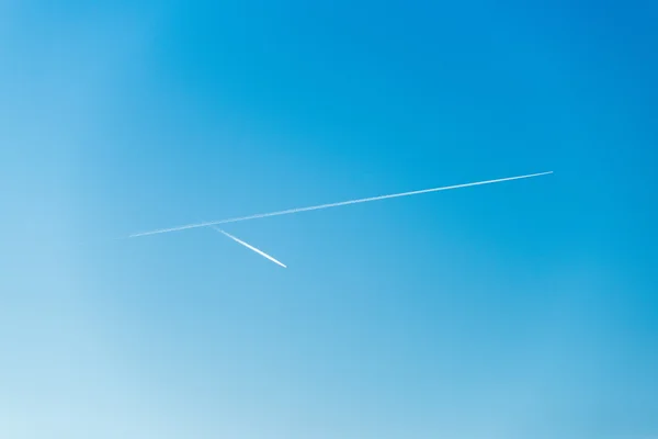 O avião voa baixo no céu, deixando um rastro branco — Fotografia de Stock