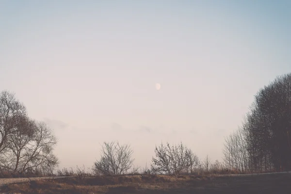 冬季日落, 月亮和飞机在天空中的足迹。老式 — 图库照片