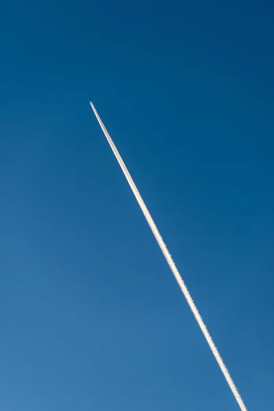 L'avion vole bas dans le ciel, laissant une traînée blanche — Photo