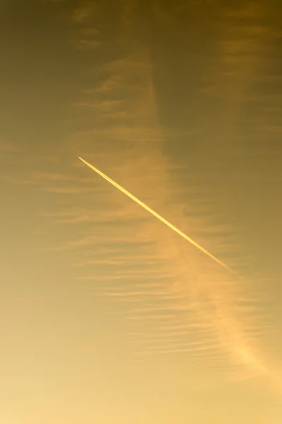 L'avion vole bas dans le ciel, laissant une traînée blanche — Photo